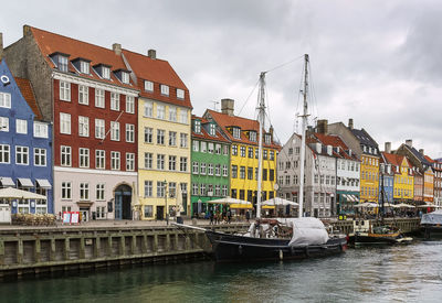 Buildings by river against sky in city