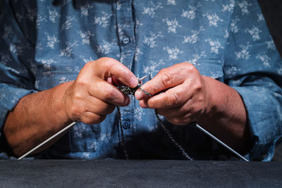 Midsection of woman knitting wool at home