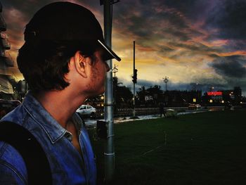 Portrait of young man looking away against sky at night