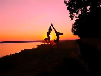 Silhouette man with arms raised against sky during sunset