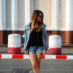 Young woman standing on road in city against building