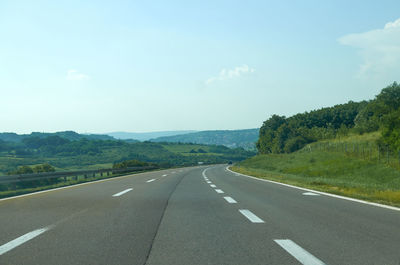 Empty road along landscape against sky