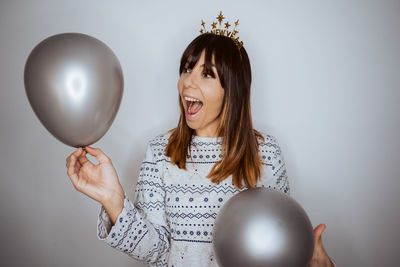 Portrait of young woman with balloons against wall