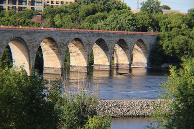 Arch bridge over river against trees