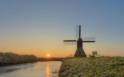 Traditional windmill against sky during sunset