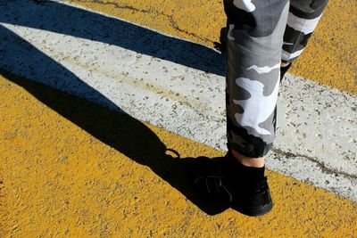 Low section of person standing on yellow shadow