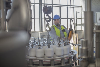 Man wearing hard hat operating control in factory