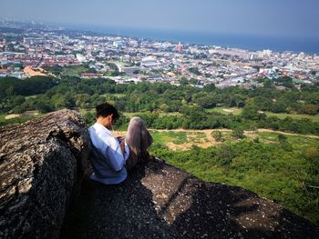 Rear view of woman looking at cityscape against sky