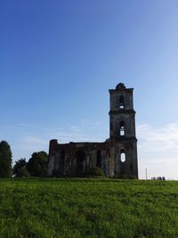 View of castle on field against blue sky