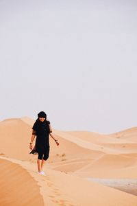 Smiling woman walking on sand dunes at desert
