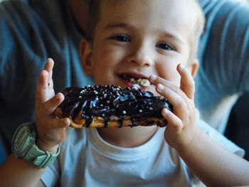 Pretty caucasian boy eating an eclair