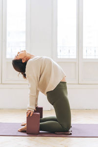 Attractive middle aged brunette woman in sportswear ptactice yoga with equipment 