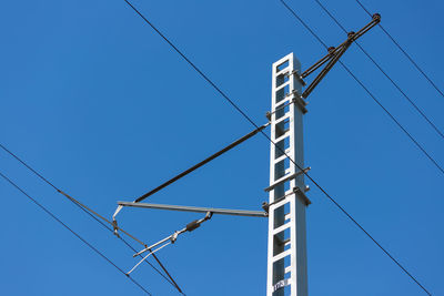 Low angle view of electricity pylon against blue sky