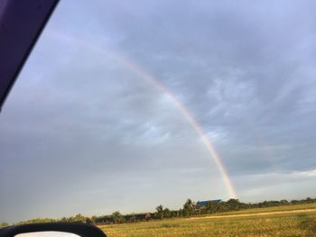 Scenic view of rainbow over field against sky