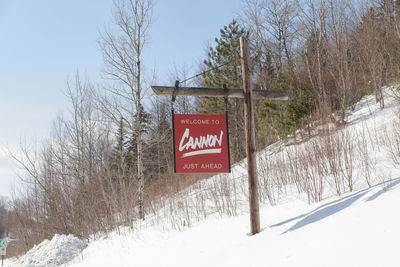 Information sign on snow covered land against sky