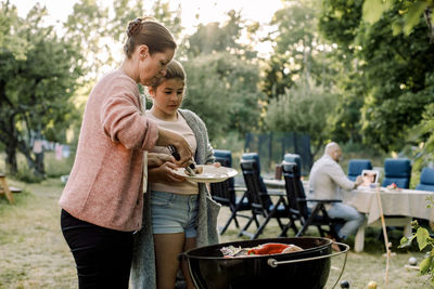 Friends standing on barbecue grill