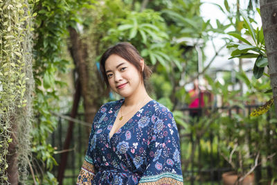 Portrait of young woman standing against plants