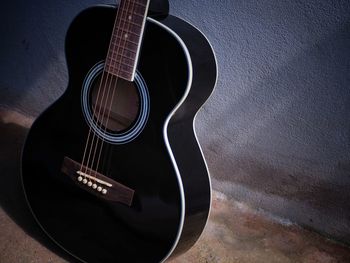 Close-up of guitar on table against wall