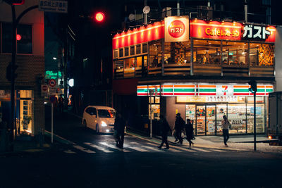 People walking on illuminated city at night