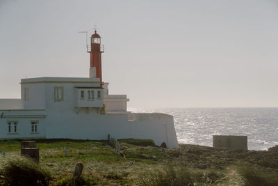 Lighthouse amidst sea and buildings against sky