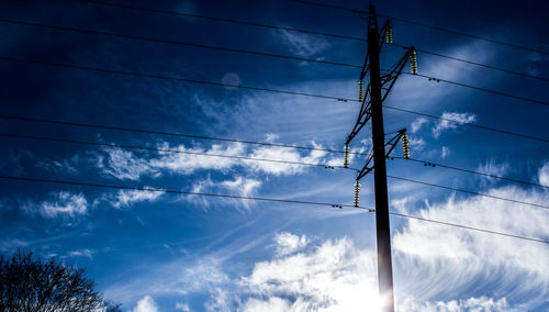 Low angle view of electricity pylon against cloudy sky