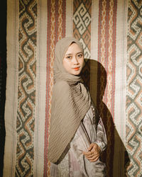 Portrait of young woman standing against wall