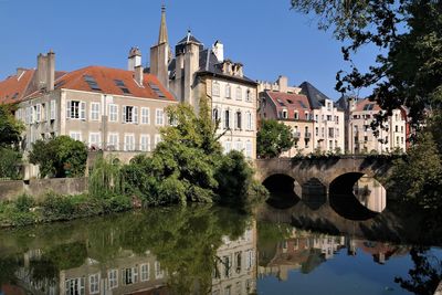 Arch bridge over river by buildings against sky