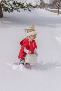 High angle view of cute girl carrying purse while standing on snowy field