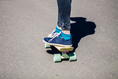 Low section of woman skateboarding on road