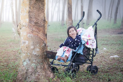Portrait of girl sitting on tree trunk