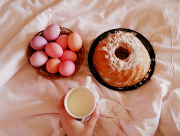Cropped image of person holding milk cup with eggs and food on bed