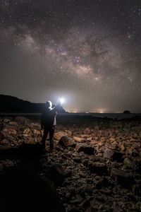 Rear view of man standing on rock against sky