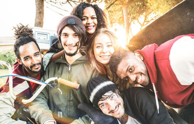 Portrait of cheerful friends against trees during sunset