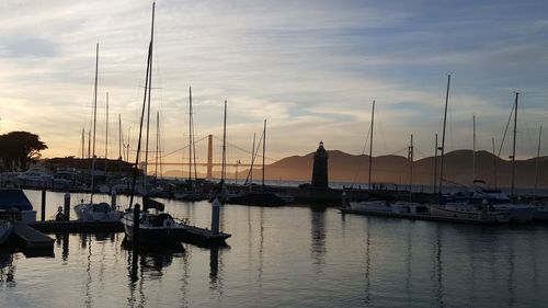 Sailboats moored in marina at sunset
