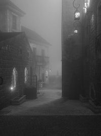 Illuminated street light on footpath by building at night