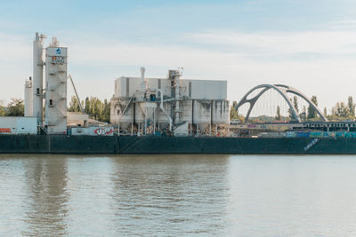 View of harbor by river against sky