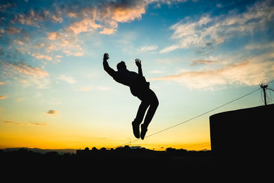 Silhouette man jumping against sky during sunset