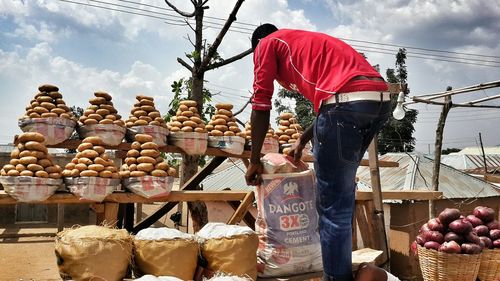 Rear view of street market vendor with potatoes on stall against sky