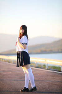 Full length of beautiful young woman wearing uniform while standing on road
