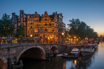 Arch bridge over canal amidst buildings in city