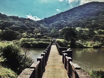Boardwalk by lake against sky