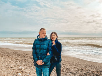 Friends standing on beach against sky