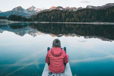 Rear view of woman looking at lake against mountains