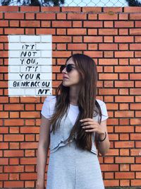 Full length of woman standing against brick wall