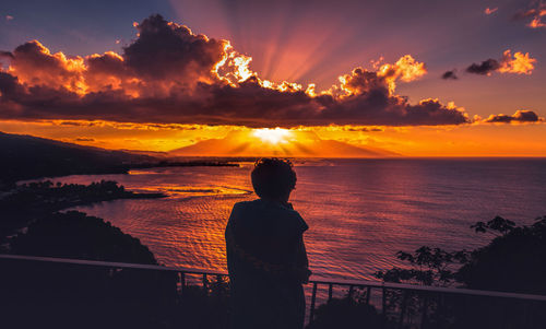 Silhouette man standing by sea against sky during sunset