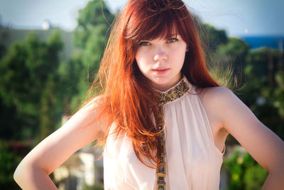 Portrait of beautiful young woman standing against trees