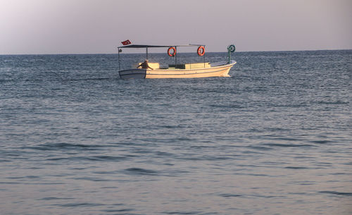 Boat sailing in sea against clear sky