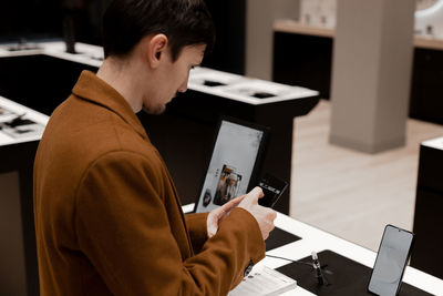 A young man examines a smartphone in a store.