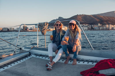 Portrait of smiling young woman sitting on boat sailing in sea