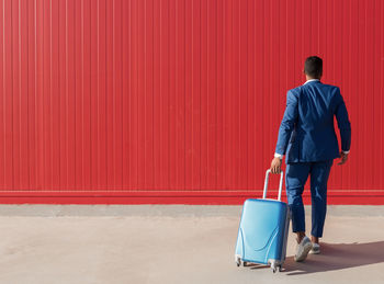 Rear view of man walking against red wall